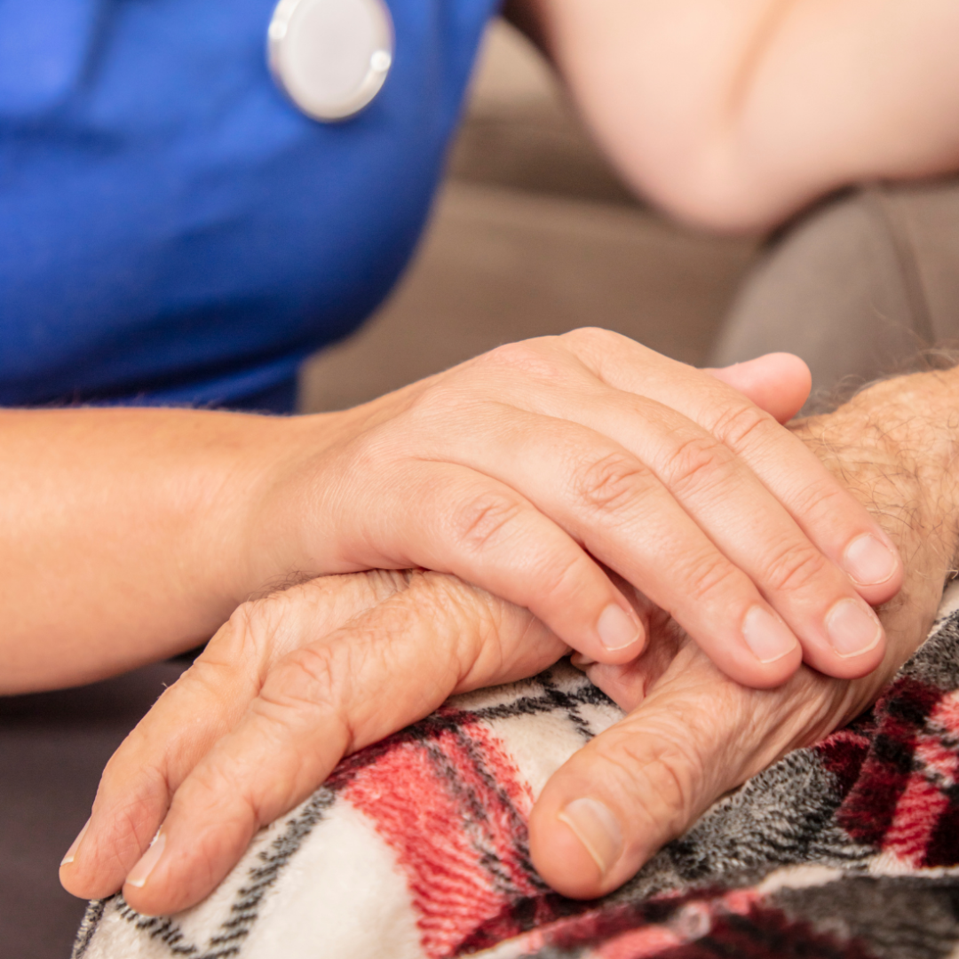 closeup of caregiver's hand resting on senior man's hand